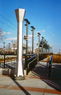 Beacon, HBLRT Station view, ©1996<br>With lighting consultant Ray Grenald and graphics designer Virginia Gehshan.  Intended to function both as an art object and as a primary identifier of stations, the beacon is modeled after the old smokestacks which were prominent in coal burning locomotives. <br>
Stainless steel, granite, plastic and lighting components. <br>
168h x 29w x 29d (inches). <br>
NJ Transit's Hudson Bergen Light Rail Stations, Hudson and Bergen Counties, New Jersey